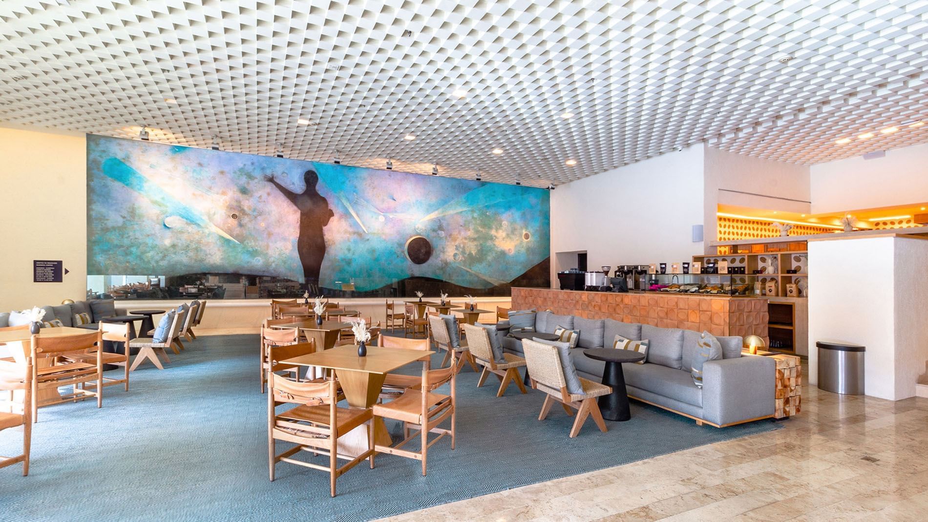 Café Tamayo featuring a large blue mural, grey sofas, and wood accents at Camino Real Polanco Mexico
