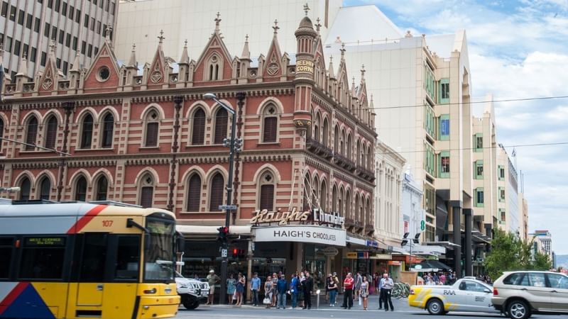 Busy street intersection in Adelaide CBD with historic buildings nearby.