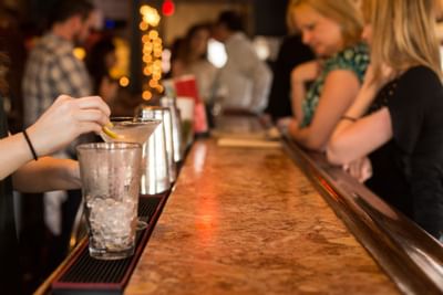 Bartender making drinks at a bar counter in The Inn at Saratoga