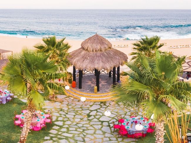 Aerial view of a scenic beach wedding setup at Hacienda del Mar Los Cabos with a palapa, tables, and ocean view