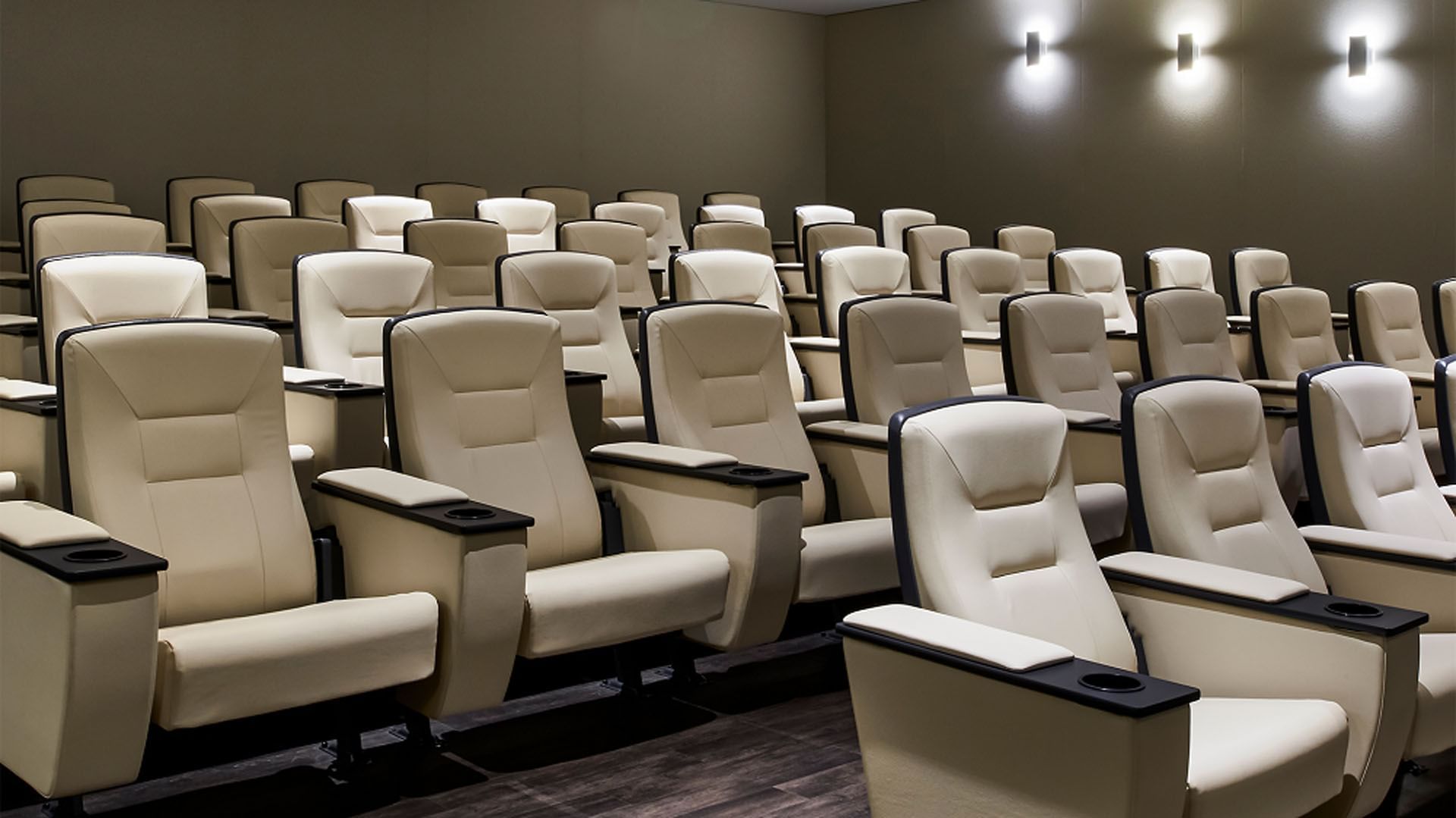 Rows of comfortable cream leather theater seats facing wall inside private screening room at Hotel X Toronto hotel