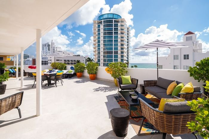 Vibrant rooftop patio with stylish seating overlooking the ocean and high-rise buildings at Tradewinds Apartment Hotel