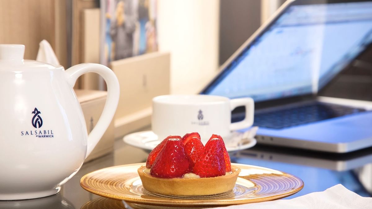 Strawberry pie served with tea on a working desk in the Executive One-Bedroom Suite at Warwick Hotel Jeddah