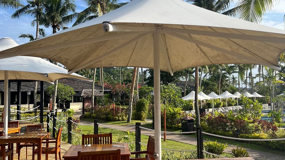 Outdoor dining area under large umbrellas at Lagoon Terrace Restaurant, Warwick Le Lagon - Vanuatu, Efate.