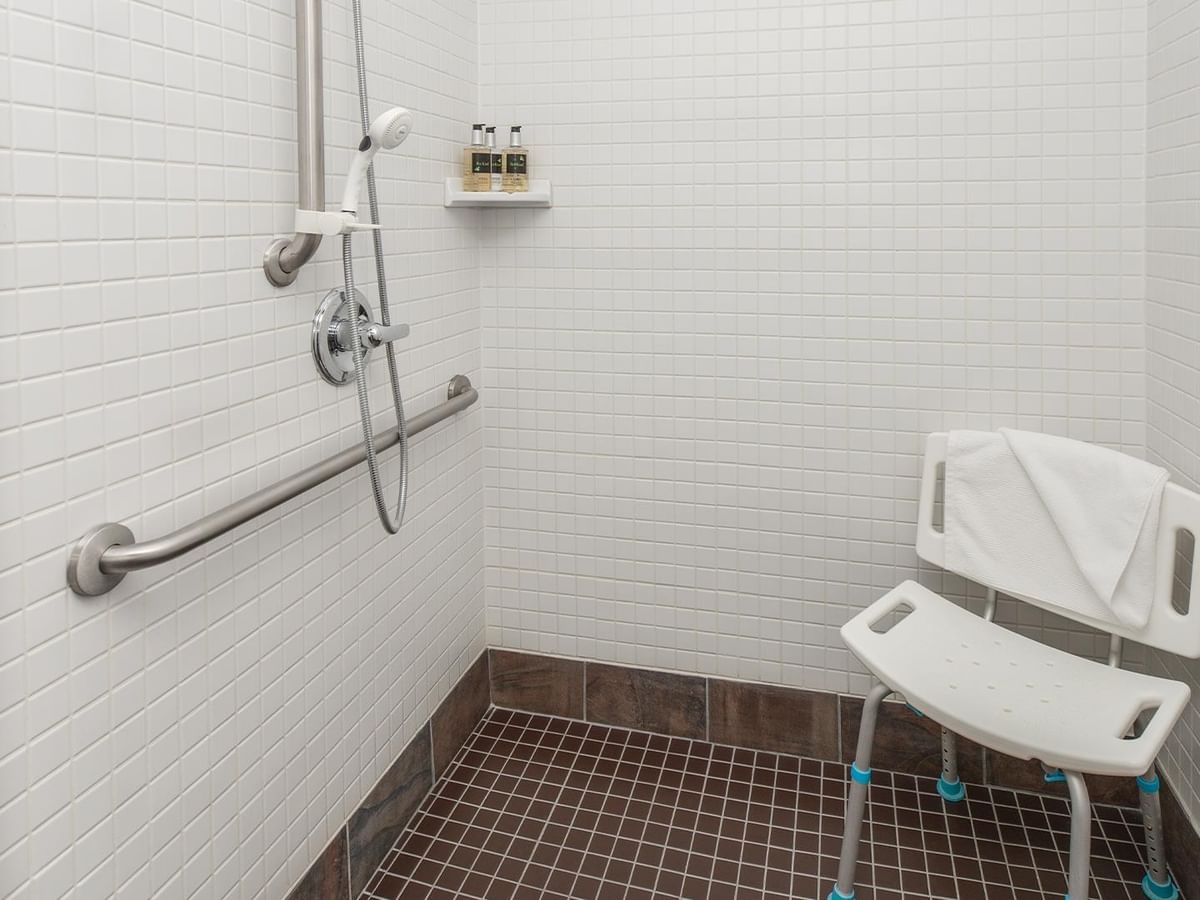 Accessible shower stall with grab bars and shower chair.