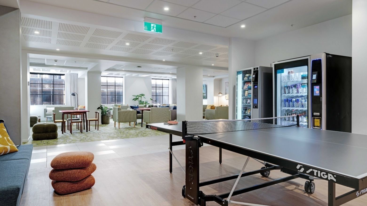 Modern communal lounge with ping pong table, vending machines, and seating areas at UniLodge Auckland Central.