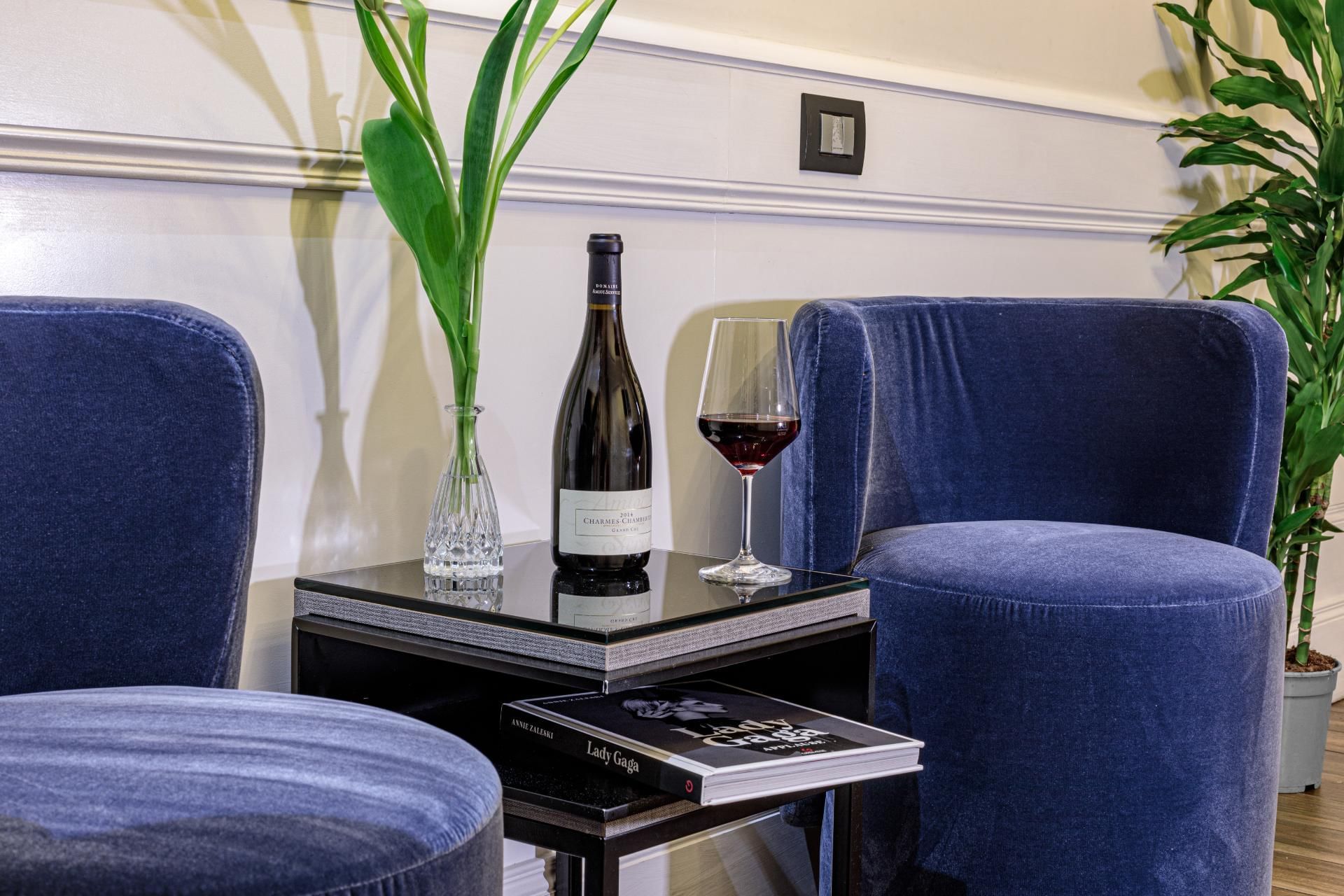 Cozy seating area in Family Room at The Independent Suites with two plush chairs, a black table with red wine, and a glass