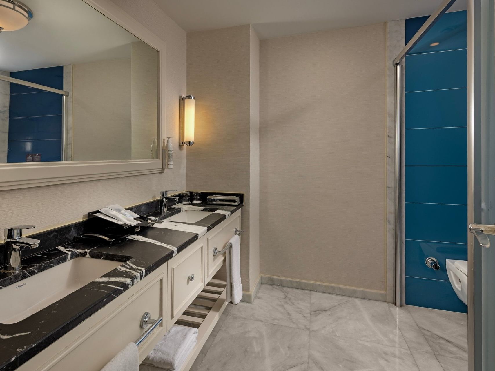 Modern bathroom with dual vanity, black marble countertops, white cabinetry, and blue tile shower at Titanic Deluxe Golf Belek