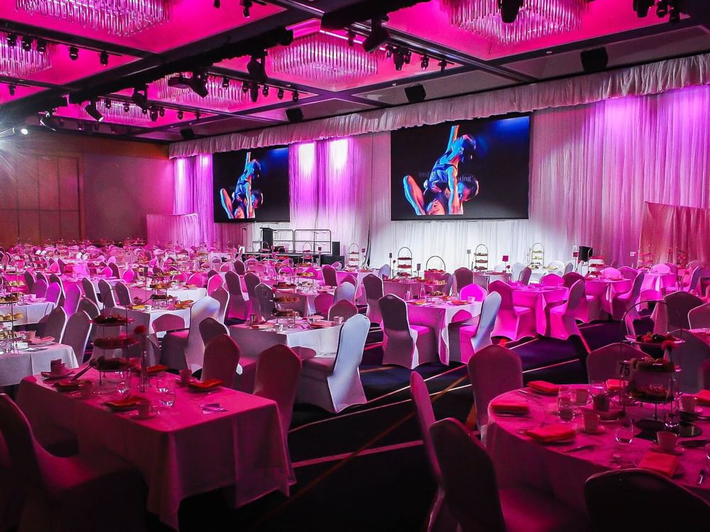 Pink color-themed spacious event room arranged with tables and chairs in Ballroom Le Grand at Sofitel Brisbane Central