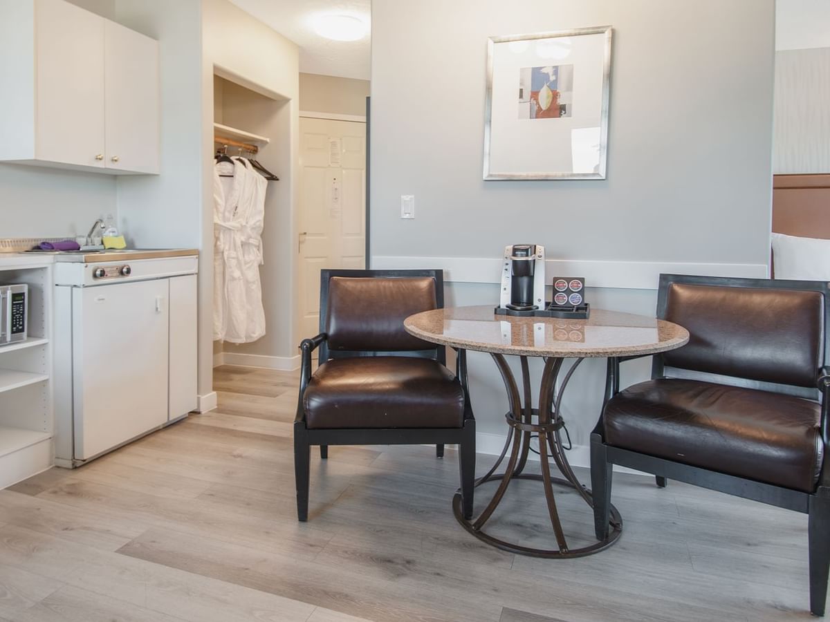 Hotel suite with table and chairs, microwave, sink, and cupboard