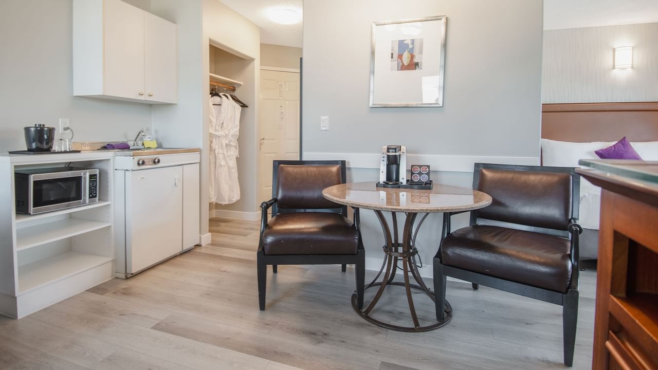 Hotel suite with table and chairs, microwave, sink, and cupboard
