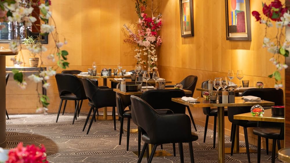 Elegant restaurant Le W with flower decorations and gold tables at Warwick Champs-Elysees Paris.