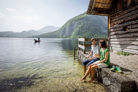 A couple sitting at a cottage by a lake near Schloss Hotel