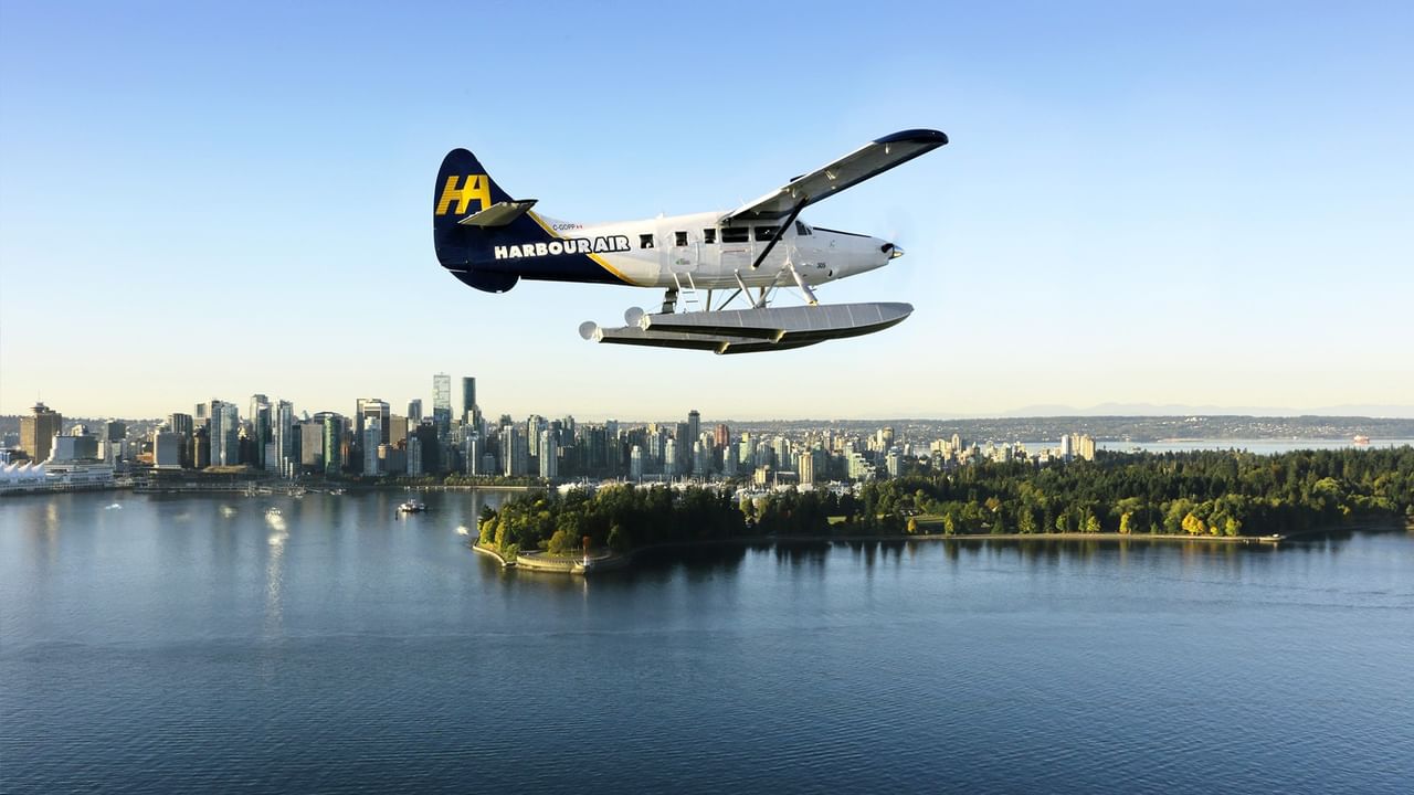Harbour Air seaplane flying above Vancouver city and waterbody at dawn or dusk.