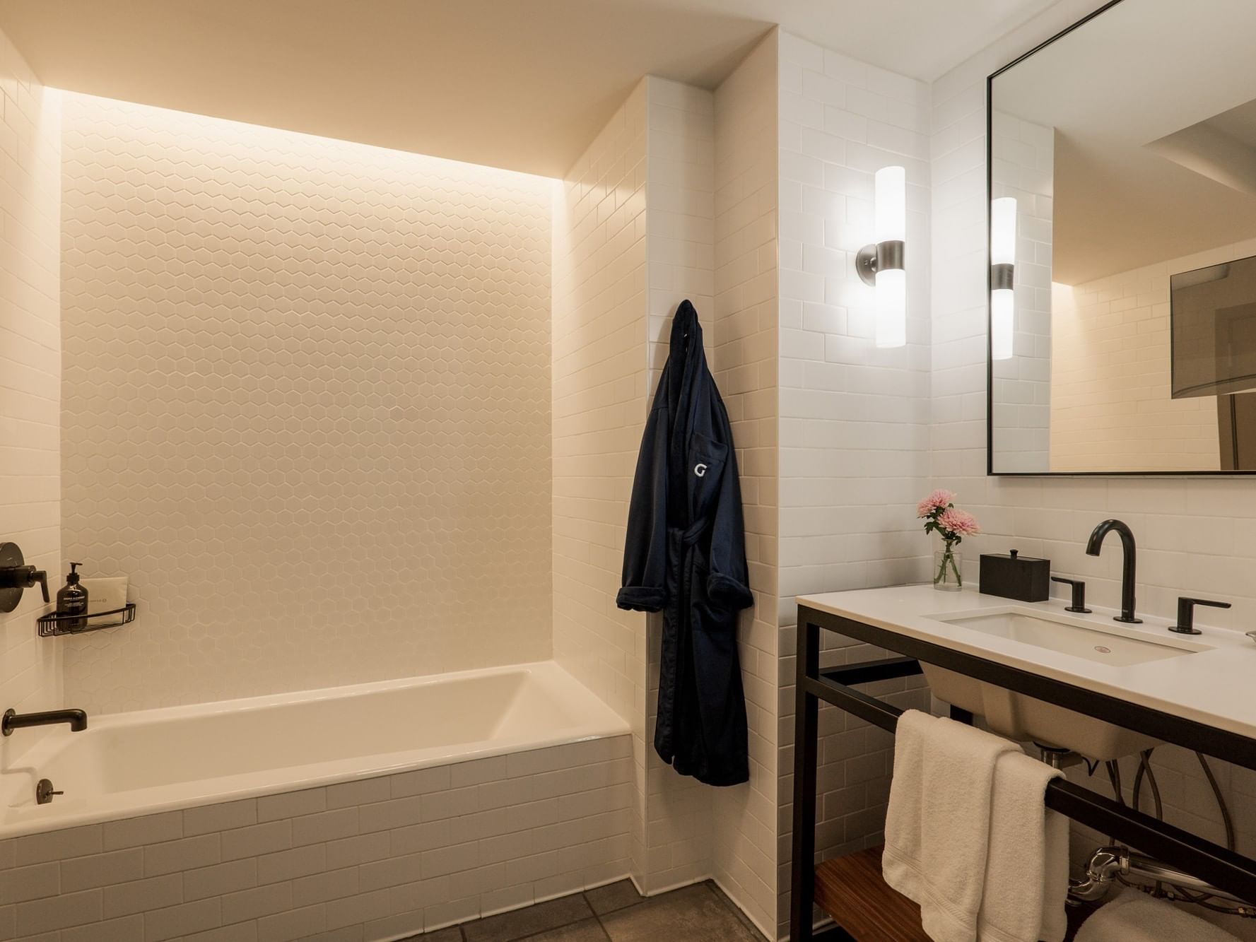 Modern white bathroom with bathtub, vanity, and mirror at Gansevoort Meatpacking NYC in New York.