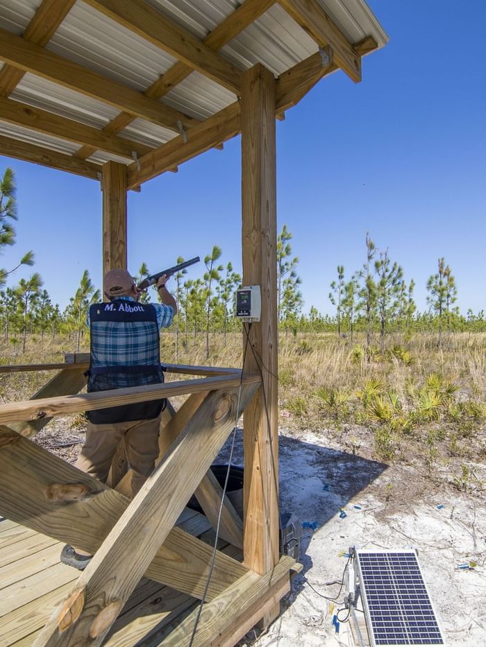 Man shooting a gun on a wooden platform in a field at Watersound Club Sporting Clays, Inlet Beach.