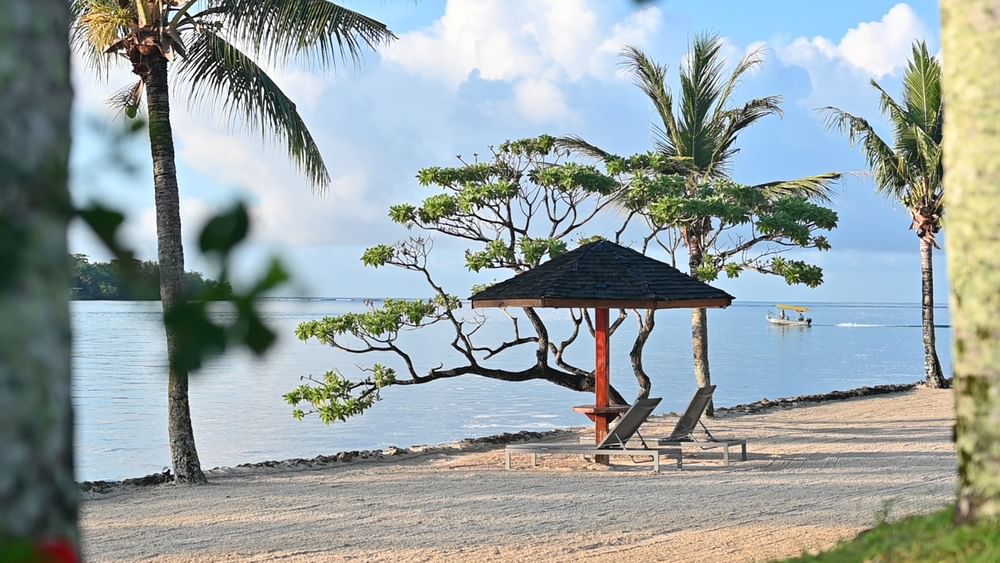 Beach loungers under a shaded umbrella at Warwick Le Lagon - Vanuatu in Efate.