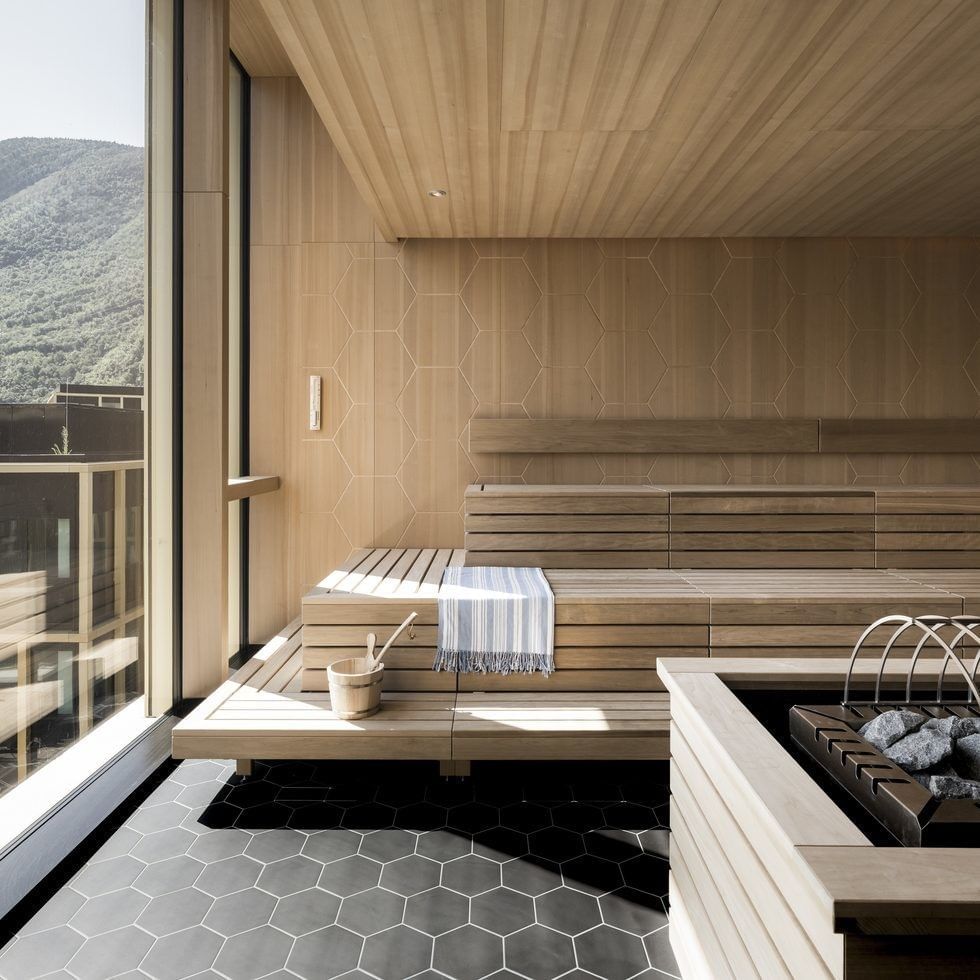 Modern wooden day spa with large windows overlooking mountains and a hex-tiled floor.