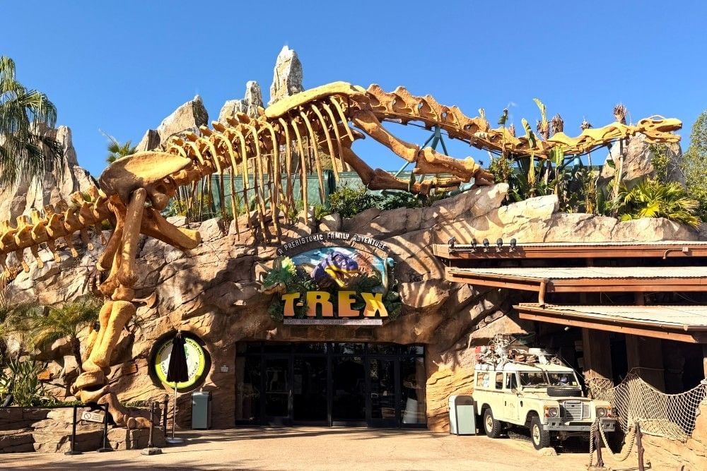 The exterior of T-Rex restaurant at Disney Springs, complete with a jeep and a towering dinosaur skeleton.