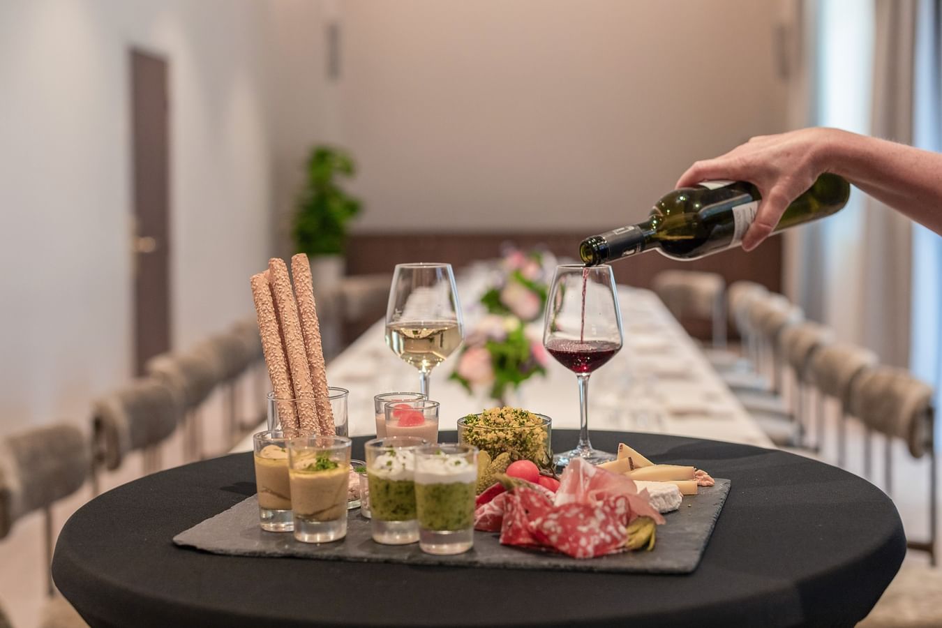 Wine being poured into a glass next to an appetizer spread at Warwick Corporate