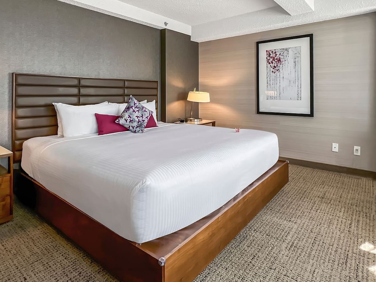 Hotel bedroom with bed, nightstand, lamp, and working desk