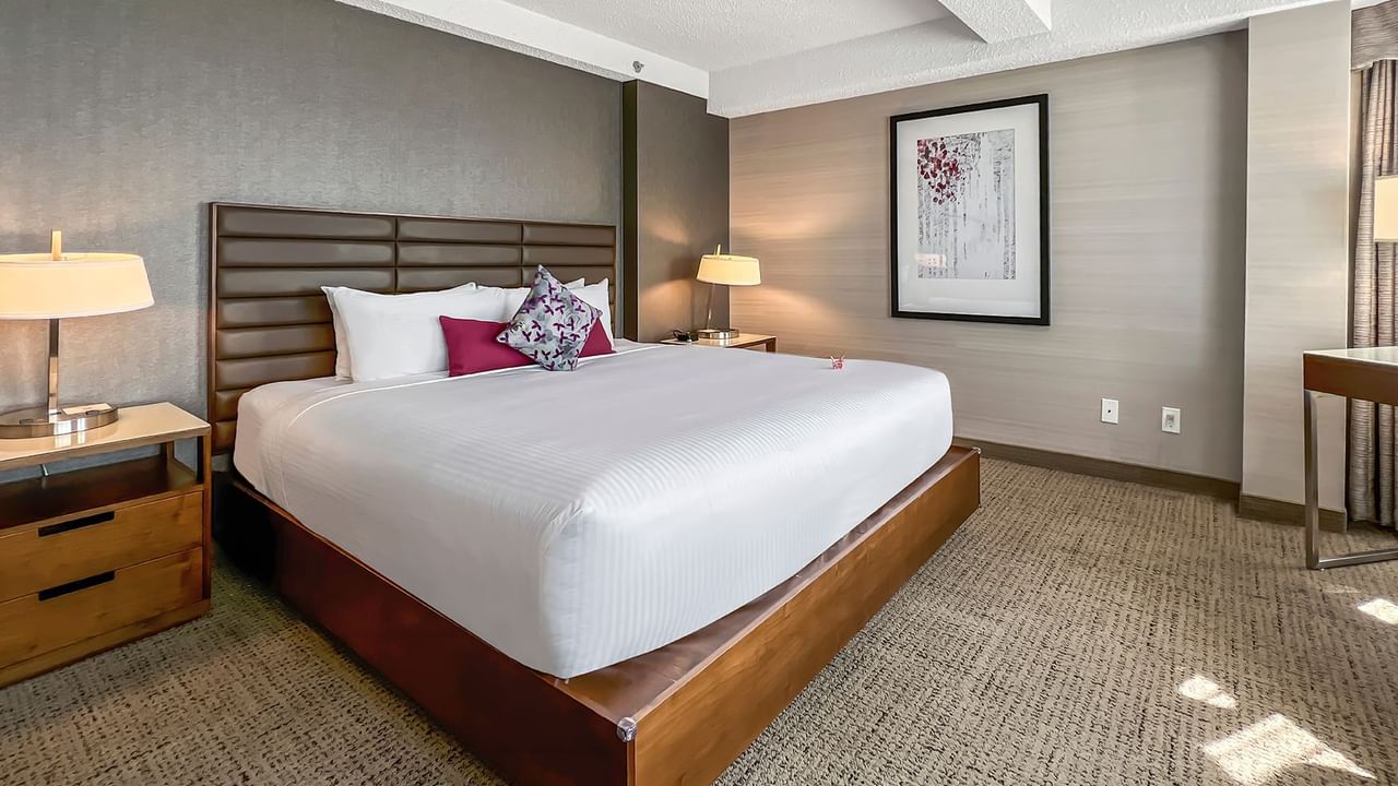 Hotel bedroom with bed, nightstand, lamp, and working desk