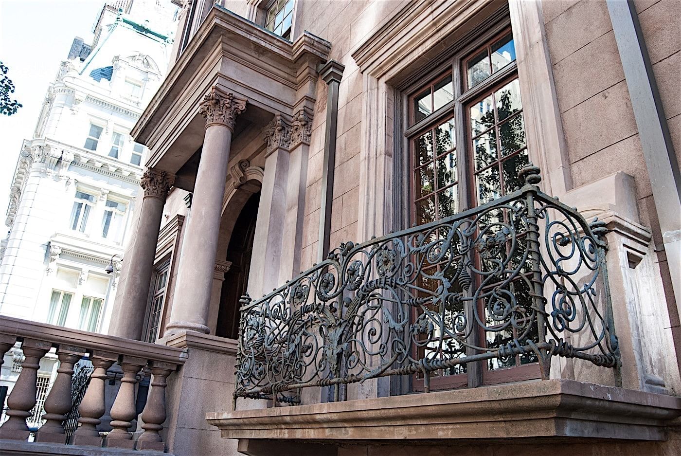 A close-up view of a balcony with an ornate railing and stone facade