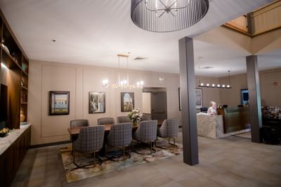 Wooden dining table with plaid chairs and reception counter with framed art at La Tourelle Hotel and Spa