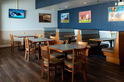 Comfortable dining area with tables, booths. and wooden flooring in Gales Restaurant in Yarmouth at Rodd Grand Yarmouth