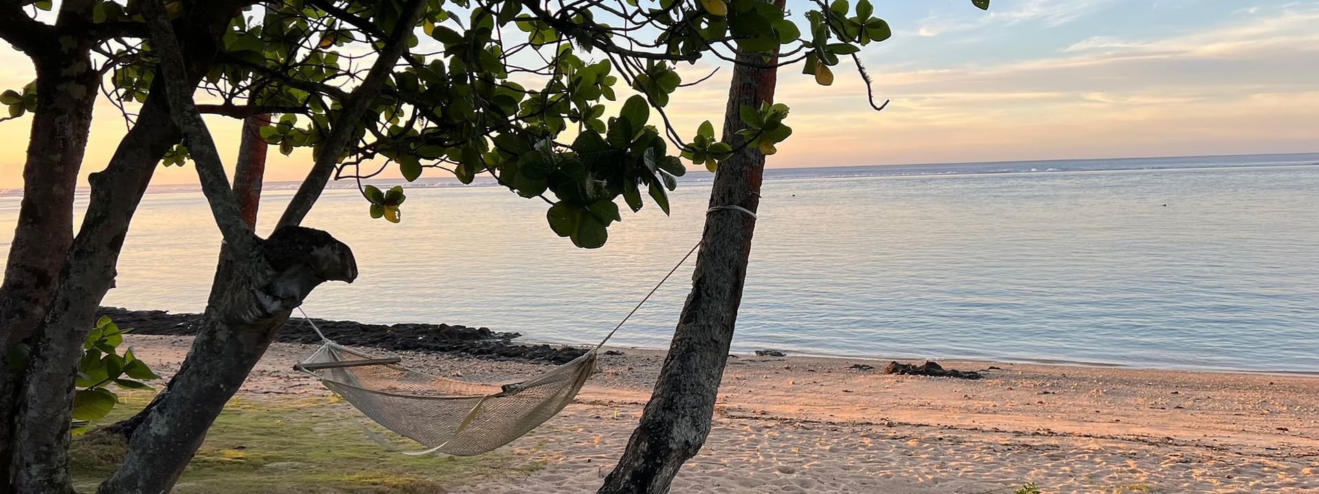 Hammock between trees on a sandy beach at Tambua Sands Beach Resort in Sigatoka