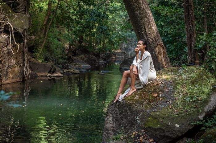 Lady sitting on a rock by the River at Hotel Rio Perdido