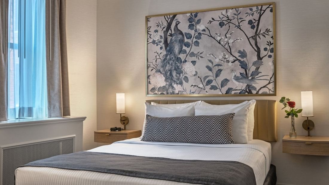 Bed with side tables under hanging wall art in Standard Room at Warwick Allerton Chicago