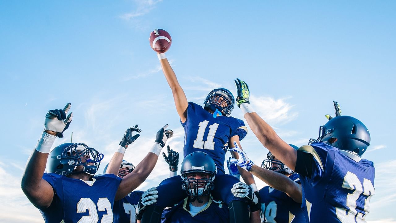 Football players in blue uniforms celebrate a touchdown.