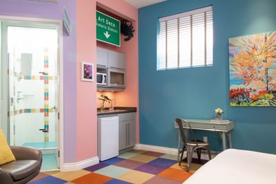 King Superior South Beach room interior with work desk, colorful carpet & kitchenette at Retro Suites Hotel