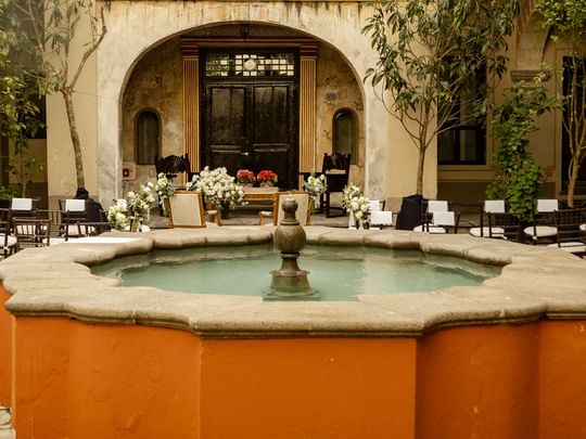 Chairs arranged for an event around a central fountain at Patio Capilla, Quinta Real Puebla, Heroica Puebla de Zaragoza.