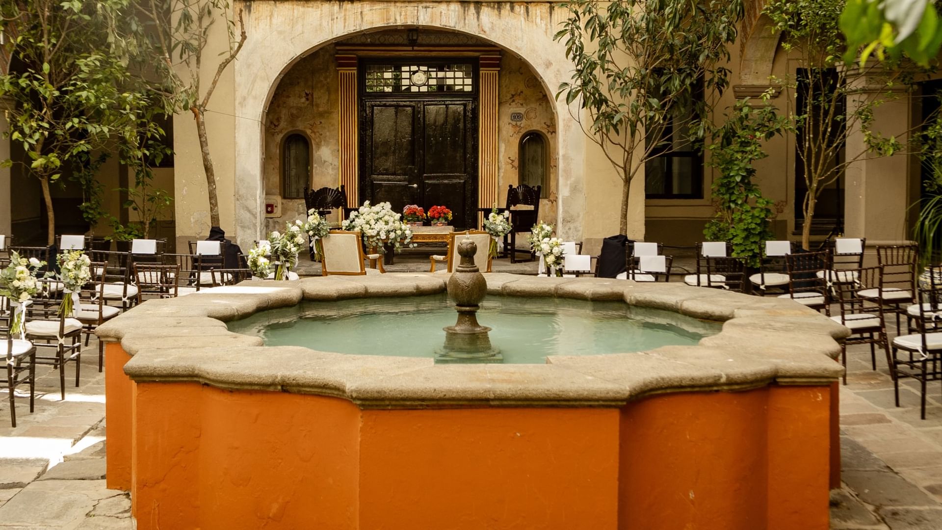Chairs arranged for an event around a central fountain at Patio Capilla, Quinta Real Puebla, Heroica Puebla de Zaragoza.