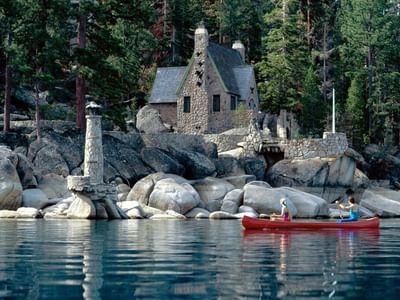 Stone Tea House and lighthouse at Emerald Bay, Lake Tahoe, with a couple canoeing in the lake near Americana Village Suites
