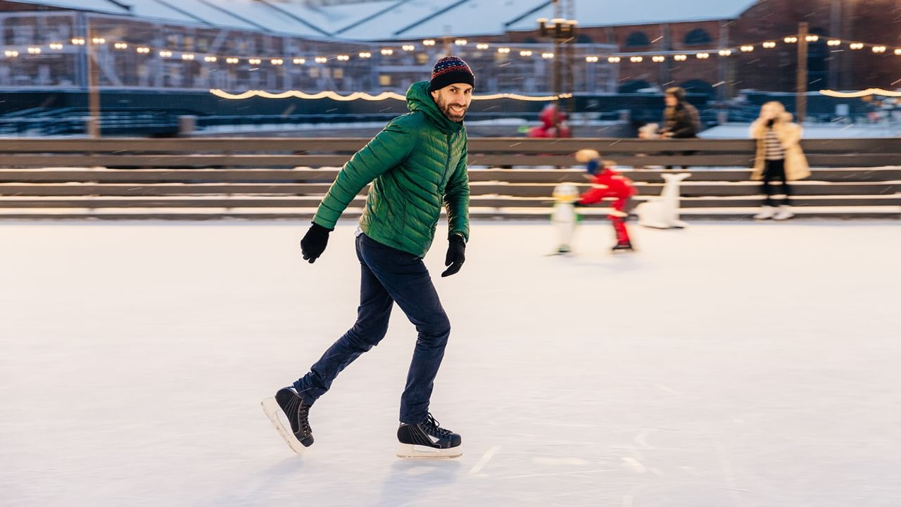 A man wearing green jacket enjoying skating in Bellevue Downtown Ice Rink