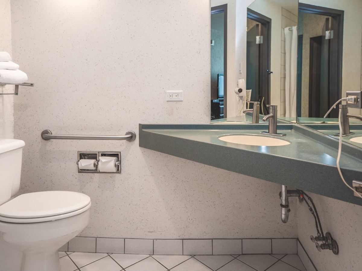Coast Accessible King bathroom with a toilet, mirror, and sink at Coast Lonsdale Quay Hotel