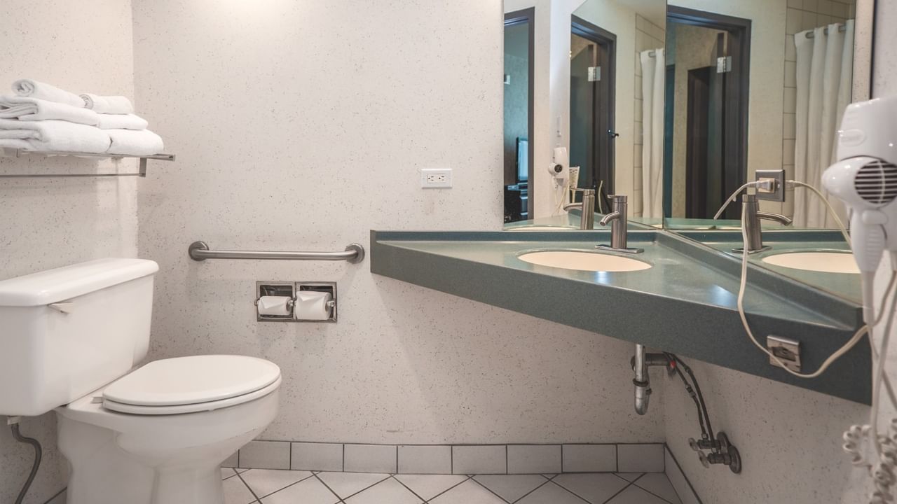 Coast Accessible King bathroom with a toilet, mirror, and sink at Coast Lonsdale Quay Hotel