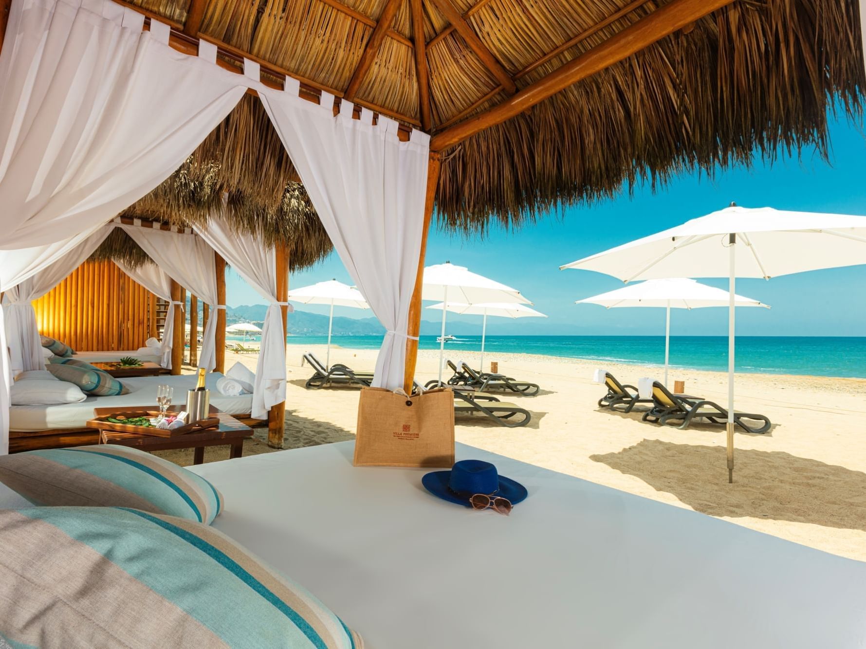 Beach cabana with drapes, sun loungers, and umbrellas on beach near Villa Premiere Boutique Hotel & Romantic Getaway