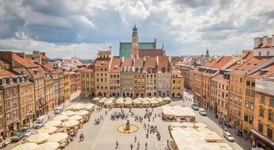 Aerial view of a bustling square with colorful buildings on a sunny day near Polonia Palace Hotel