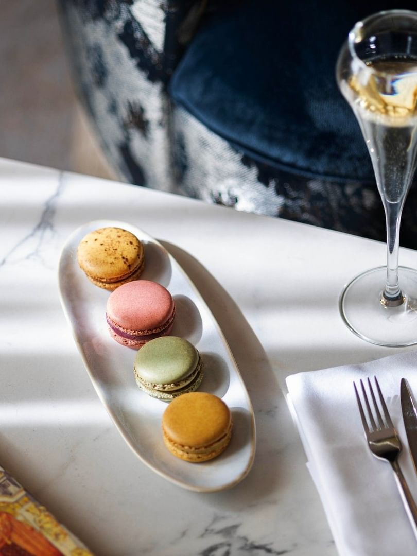 Champagne, macarons, and silverware on a table at Hôtel Westminster Paris.