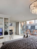 Elegant Penthouse with a grey bed by built-in TV shelving and large windows at The Capital Hotel, Apartments & Townhouse