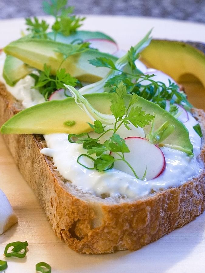 Avocado and radish slices placed with herb garnish on a toasted bread slice served at Warwick Grand Place Brussels