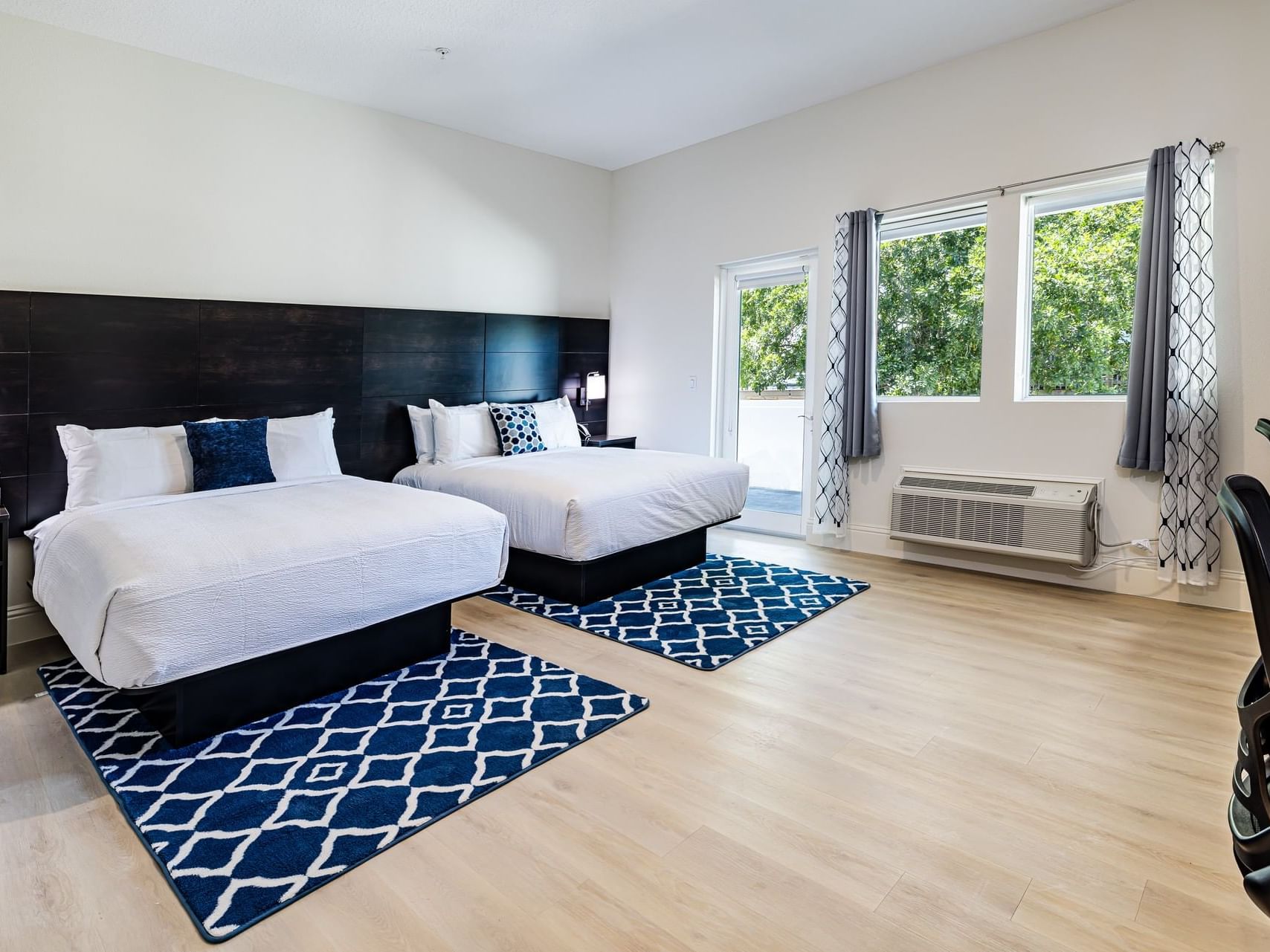 Beds featuring bedside lamps & carpeted floor in Premier Double Queen Balcony Room at Grant Street Inn