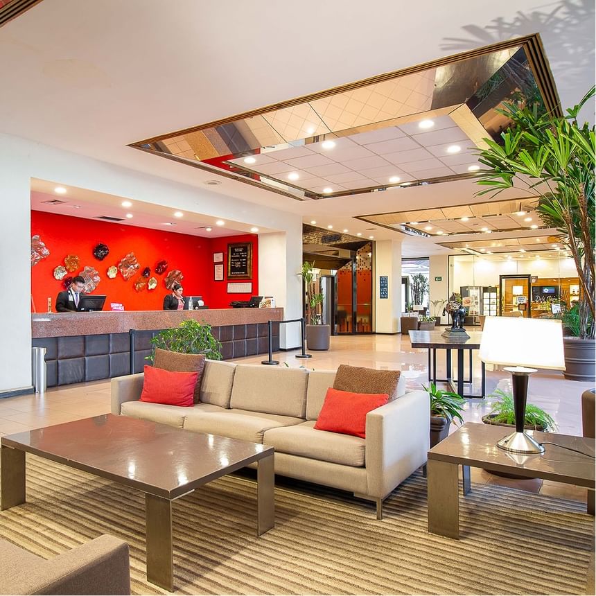 Salón de recepción elegante con sofás, mesas y recepción en Hotel Guadalajara Plaza Expo