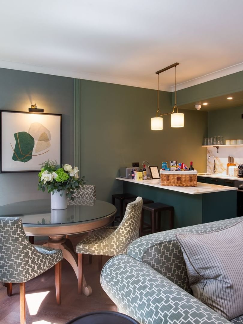 Dining table by a kitchen counter with baskets, surrounded by chairs at The Capital Hotel, Apartments and Townhouse