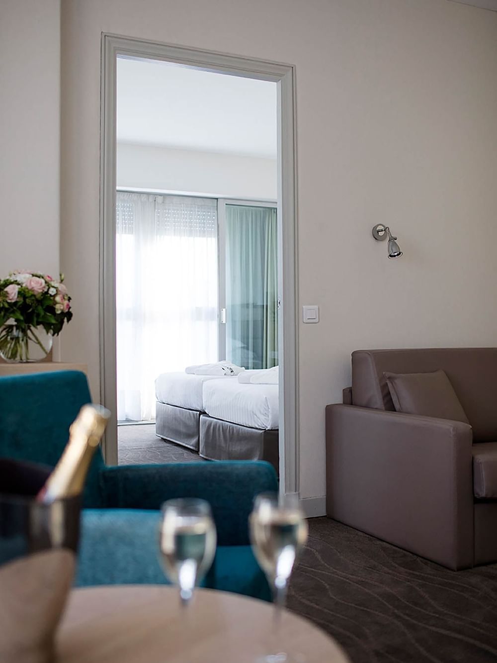 Inviting lounge area overlooking a peaceful bedroom with fresh floral decor in the Suites at Splendid Hotel & Spa Nice