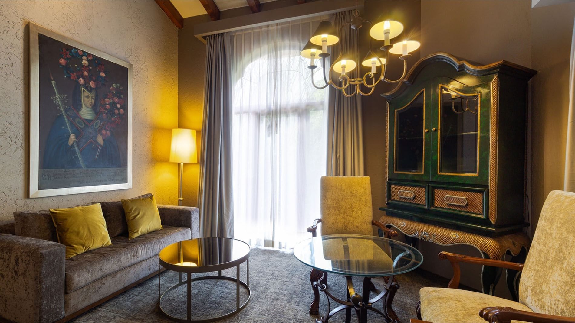King Grand Class living space with a green armoire, chandelier, and plush sofa at Quinta Real Guadalajara
